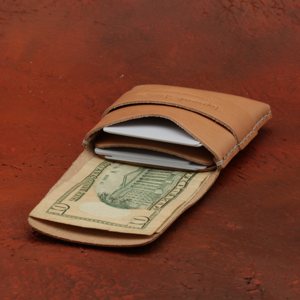 Brown leather wallet with a dollar bill on a red-brown textured background 