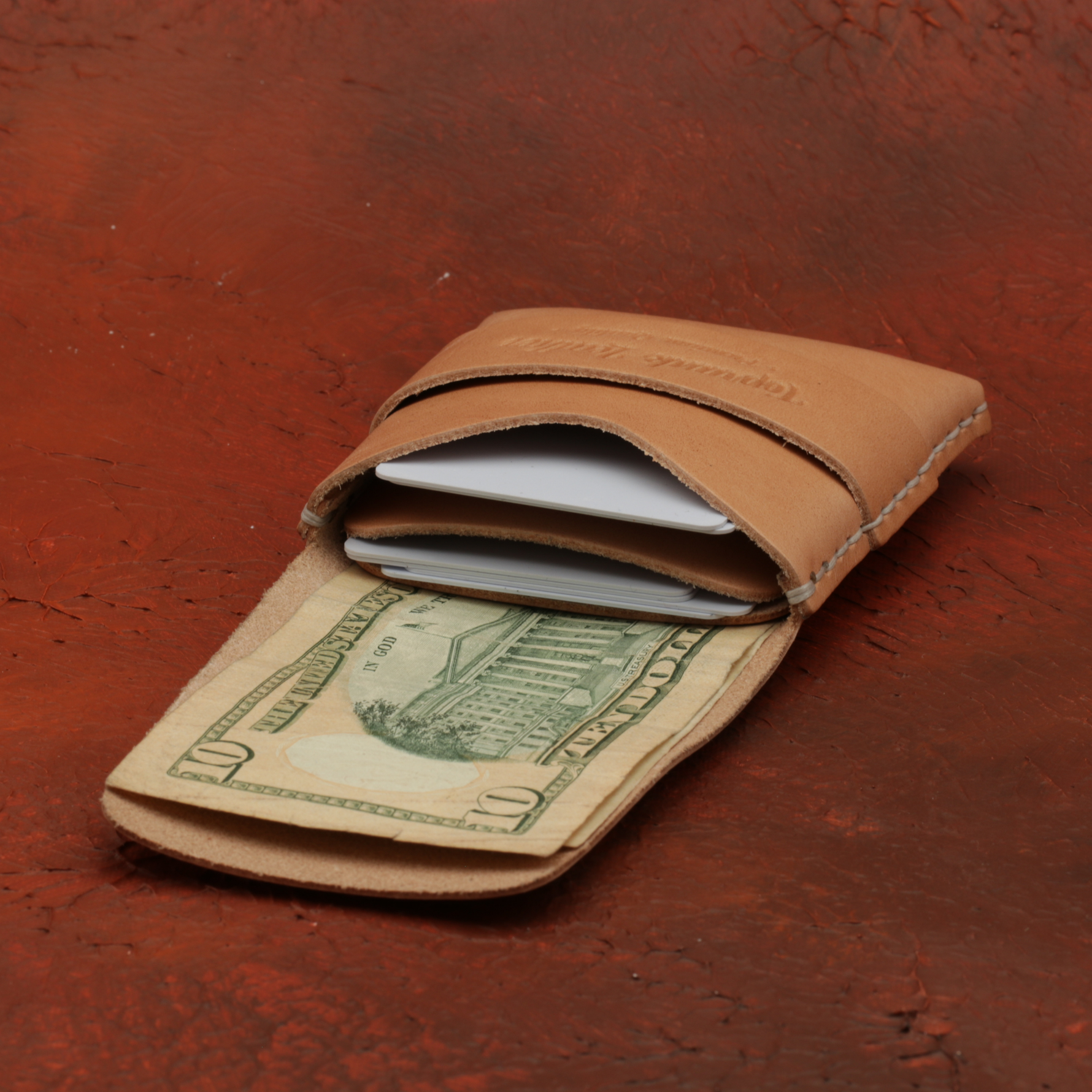 Brown leather wallet with a dollar bill on a red-brown textured background 