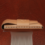 Brown leather wallet on a white stand against a textured red-brown background 