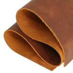 A close-up of a rolled piece of warm brown leather showing both the outer textured surface and the smoother inner side, isolated on a white background. 