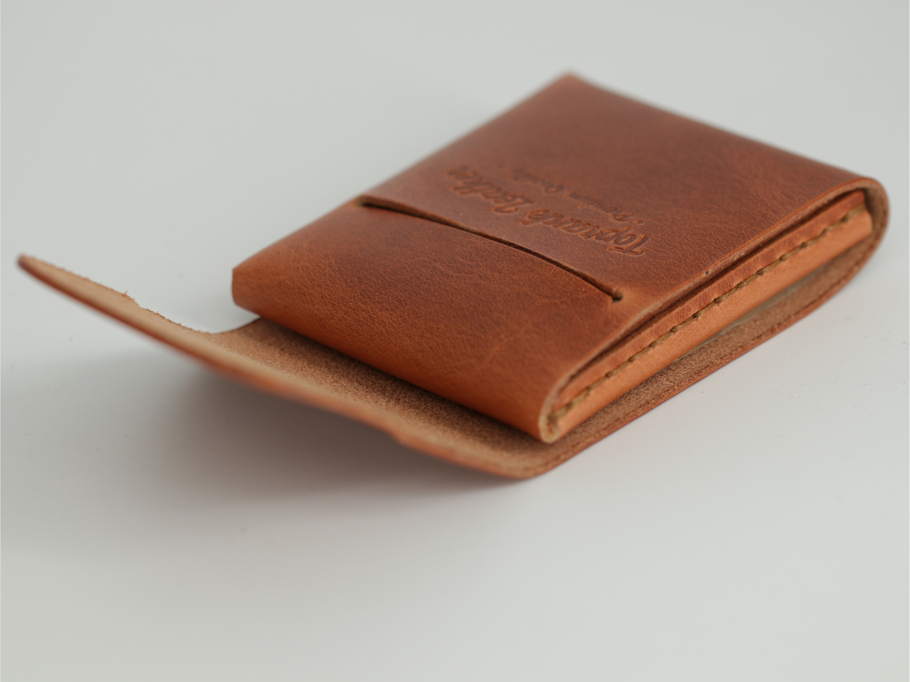 Gable leather flap wallet in Crazy Camel shown closed at an angle, with the debossed brand name. 