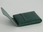 Gable leather flap wallet in Green shown closed at an angle, with the debossed logo on the flap. 