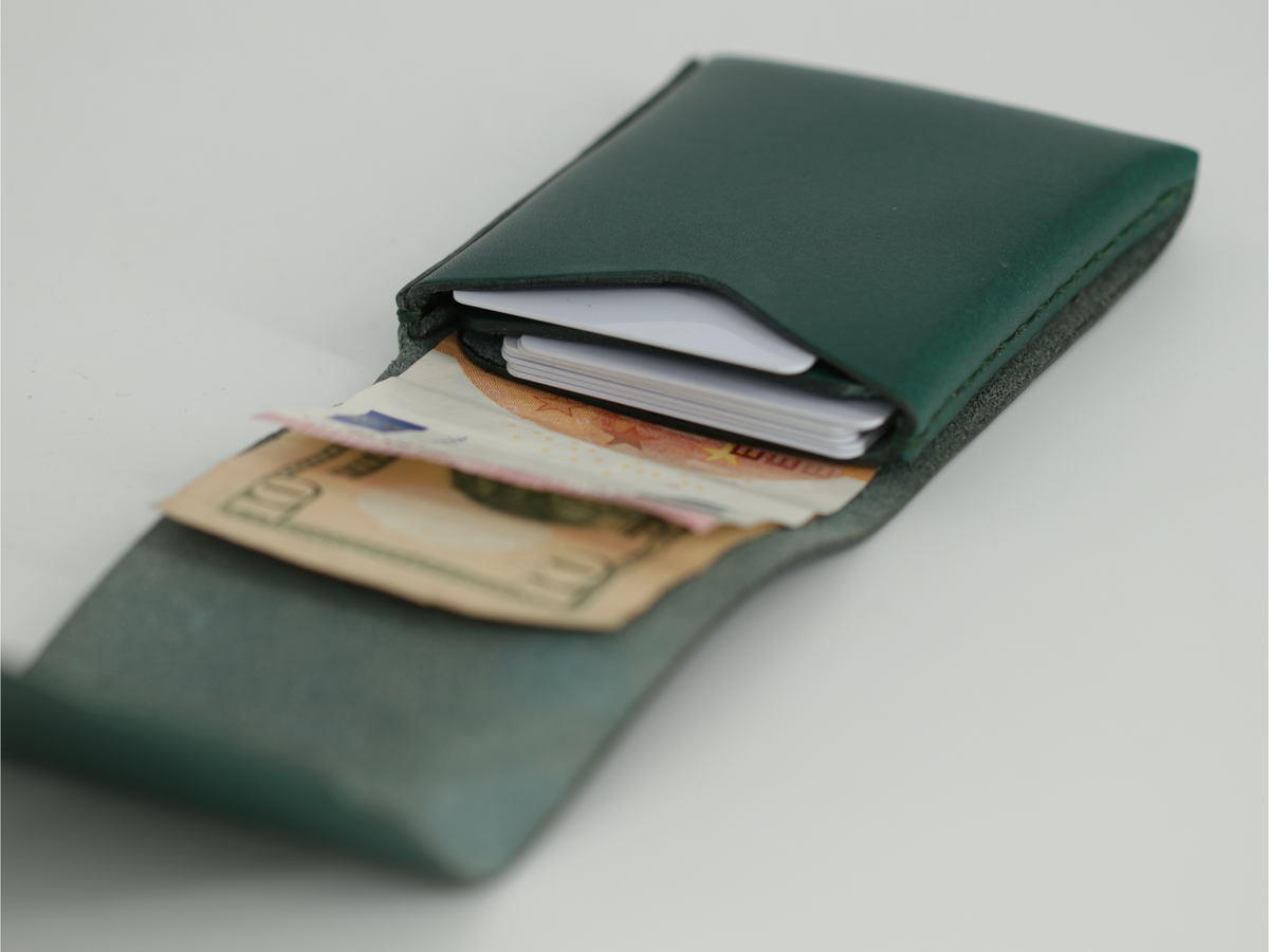 Gable leather flap wallet in Green open, with cards in the slot and bills lying flat. 