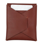 A brown leather card holder or sleeve with a diagonal fold-over flap, shown on a plain white background with a white card partially visible inside. 