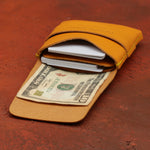 Yellow leather wallet with money and cards on a red surface 