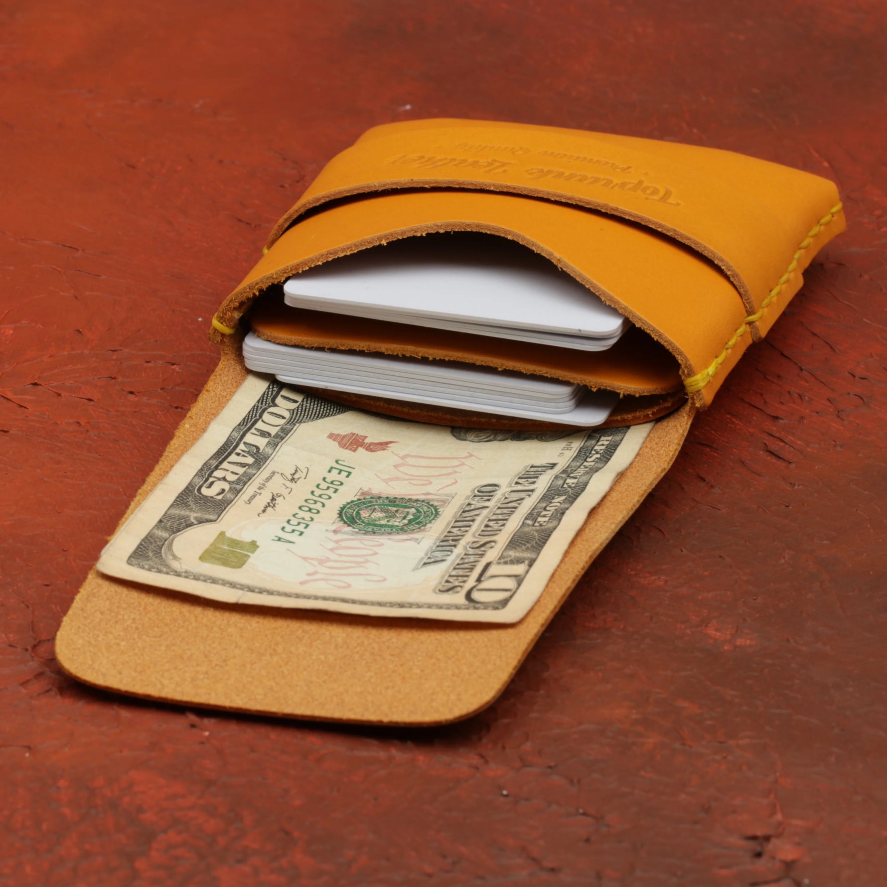 Yellow leather wallet with money and cards on a red surface 