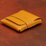 Yellow leather wallet with visible branding on a red-brown textured background 