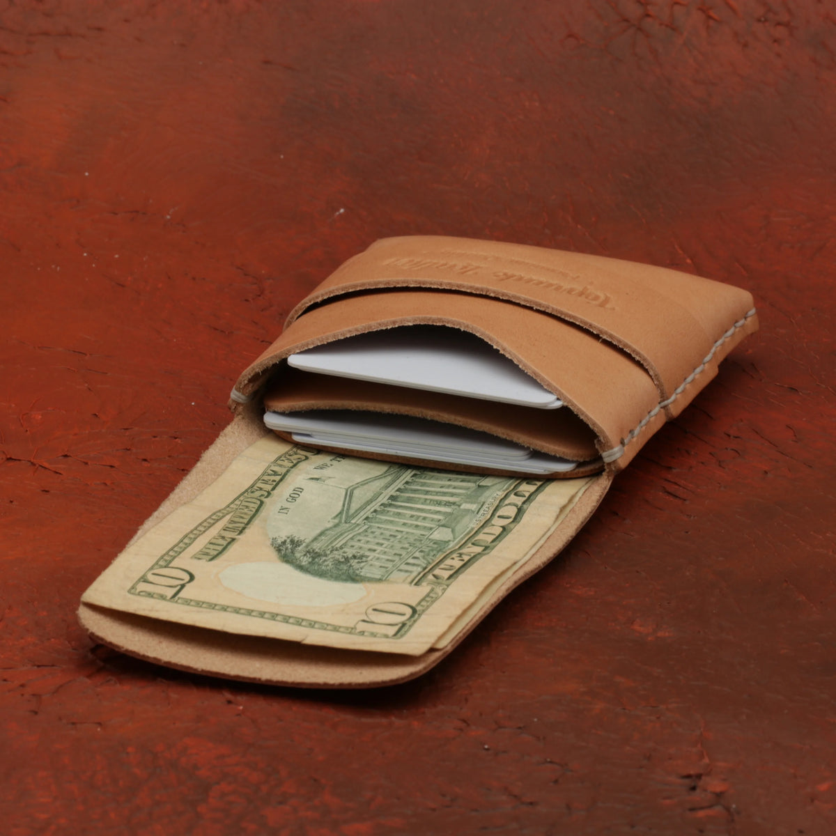 Brown leather wallet with a dollar bill on a red-brown textured background 