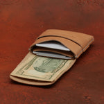 Brown leather wallet with a dollar bill on a red-brown textured background 