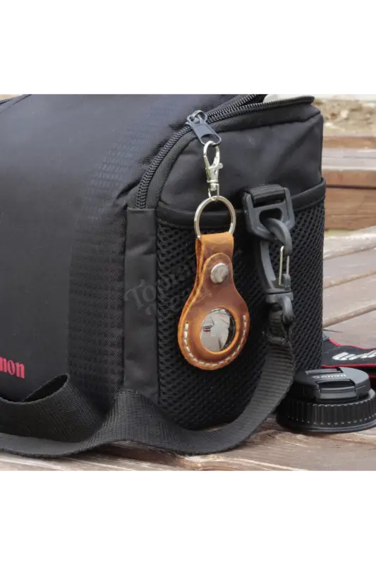 Black camera bag with a leather keychain on a wooden surface 