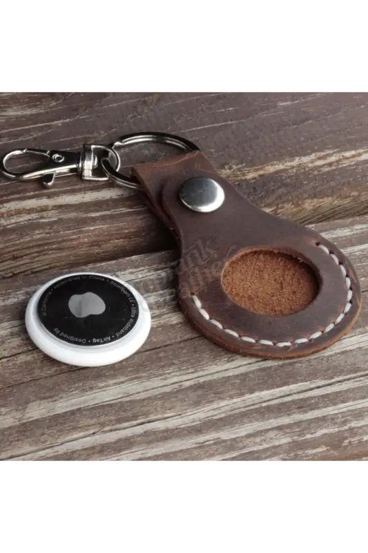 Brown leather keychain with a metal clasp on a wooden surface 