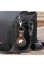 Black bag with a leather keychain attached on a wooden surface 