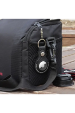Black bag with a keychain featuring a logo on a wooden surface 