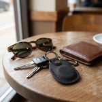 Keychain with keys, sunglasses, and wallet on a wooden table 