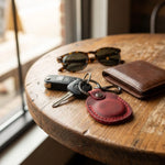Keychain with keys, sunglasses, and wallet on a wooden table 
