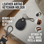 Black leather airtag keychain holder with metal clip on a concrete surface. 