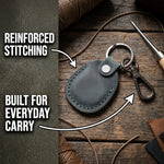 Gray leather keychain with reinforced stitching on a wooden surface 